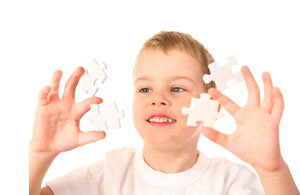 boy focused on holding jigsaw pieces